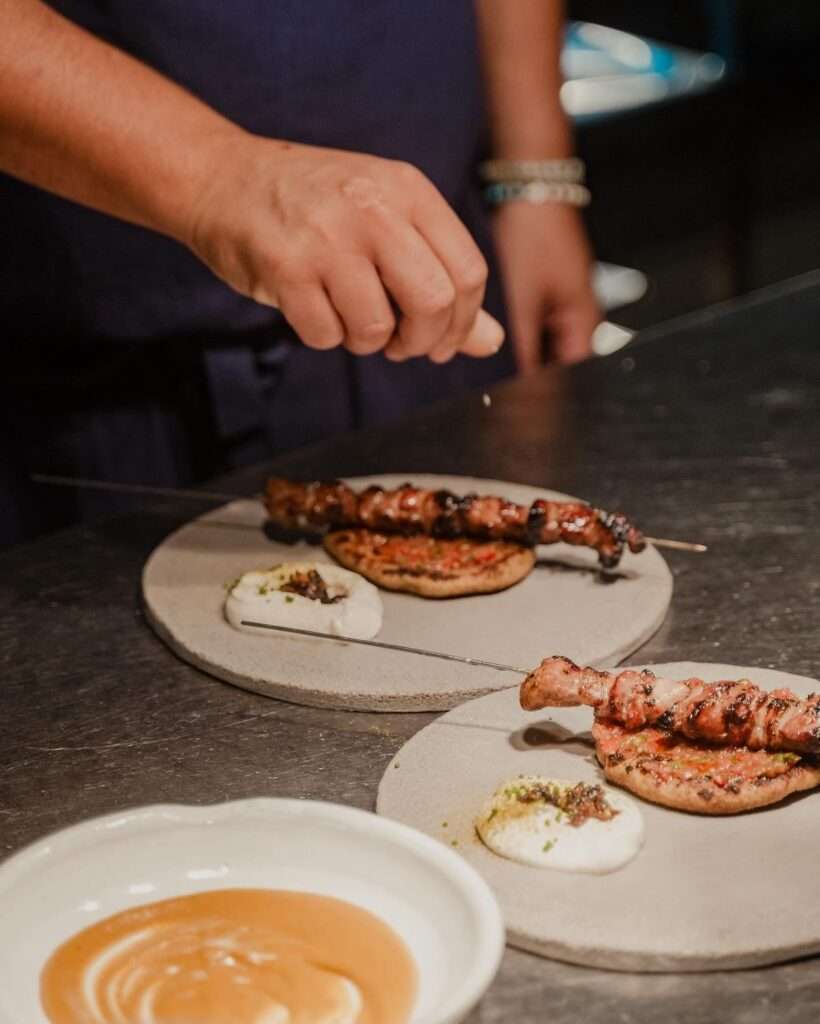 Chef finalizando kaftas no balcão de mármore com molho tahine